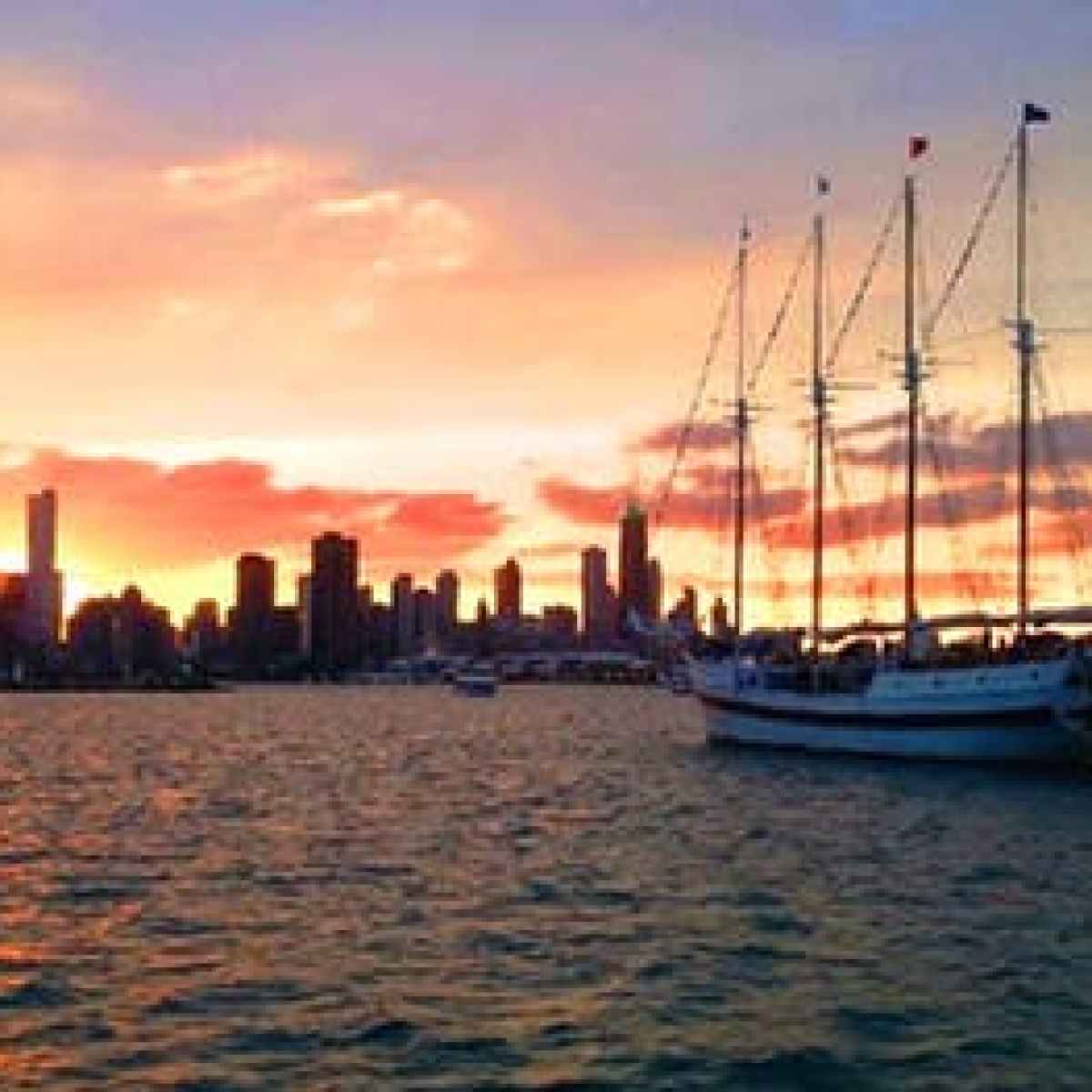 The Tall Ship Windy sailing toward the Chicago skyline at sunset