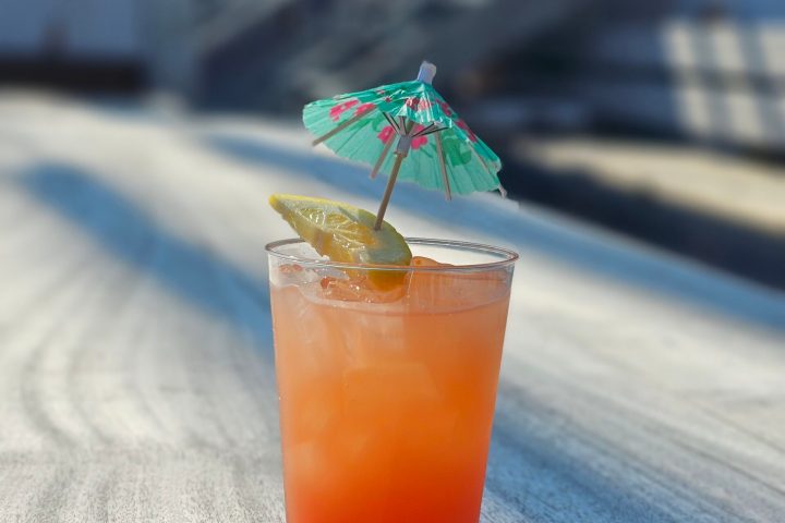 A glass of Dan Seavey's Best Punch with an umbrella on the deck of Tall Ship Windy